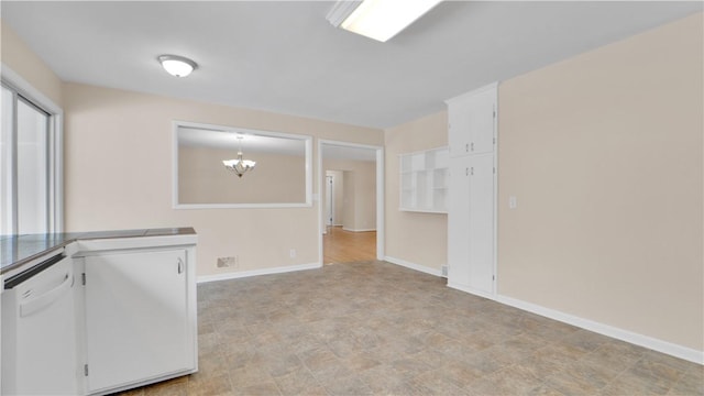 spare room featuring a chandelier and baseboards