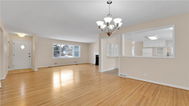 unfurnished living room featuring light wood finished floors, visible vents, a fireplace, and baseboards