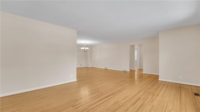 spare room featuring visible vents, baseboards, light wood-style floors, and an inviting chandelier