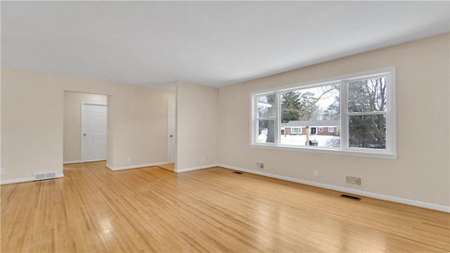 empty room featuring visible vents, baseboards, and light wood-style floors