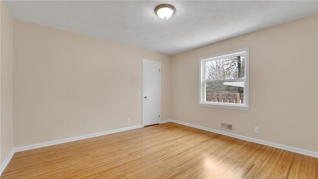 spare room with light wood finished floors, visible vents, and baseboards