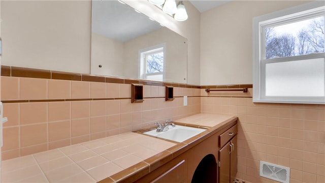 bathroom with vanity, tile walls, visible vents, and wainscoting