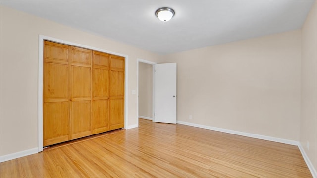 unfurnished bedroom with a closet, baseboards, and light wood-style floors