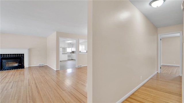 hall with wood finished floors, visible vents, and baseboards