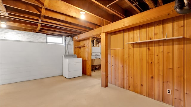 basement featuring a sink, wooden walls, and washer / dryer