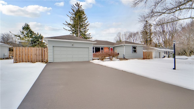 ranch-style home with an attached garage, driveway, and fence