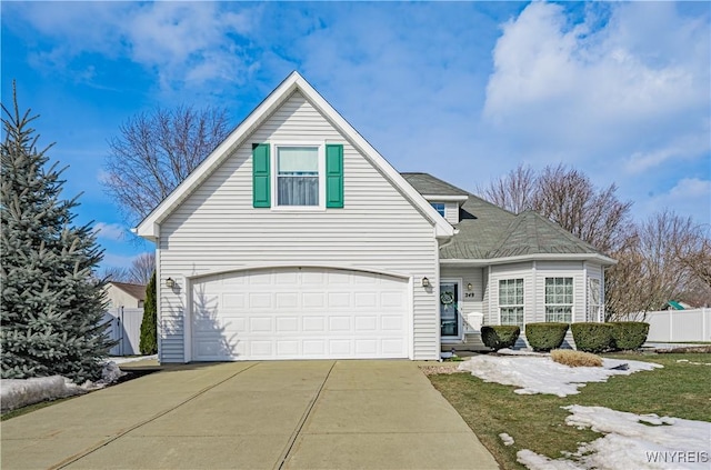 traditional-style home with concrete driveway, an attached garage, and fence