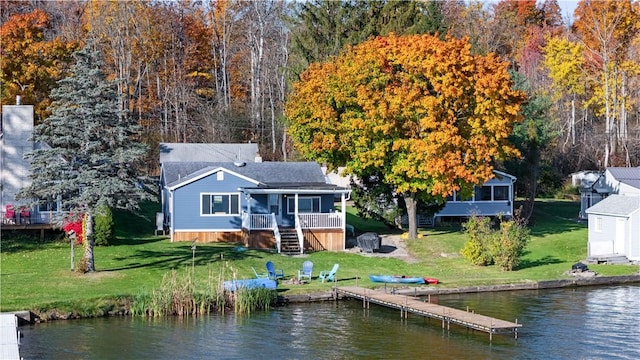 rear view of property featuring a deck with water view, a yard, and a sunroom