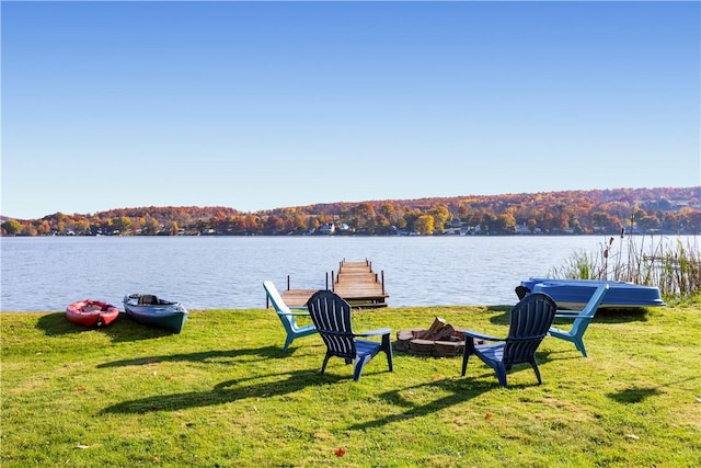 exterior space with a yard, a water view, a fire pit, and a wooded view