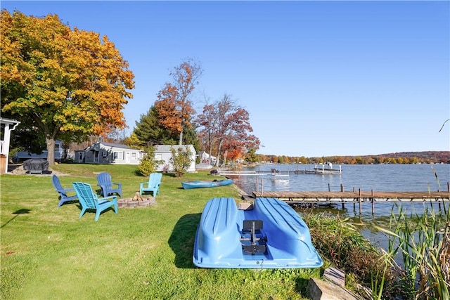 view of yard with a water view, a dock, and an outdoor fire pit