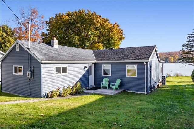 rear view of property featuring a yard, central AC, a chimney, and a shingled roof