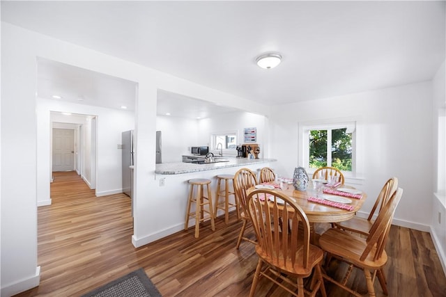 dining space with light wood-type flooring and baseboards