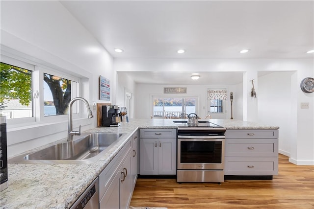 kitchen featuring light wood-type flooring, gray cabinetry, a sink, plenty of natural light, and stainless steel electric stove