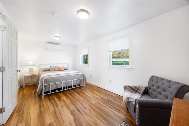 bedroom featuring an AC wall unit, baseboards, and light wood-type flooring