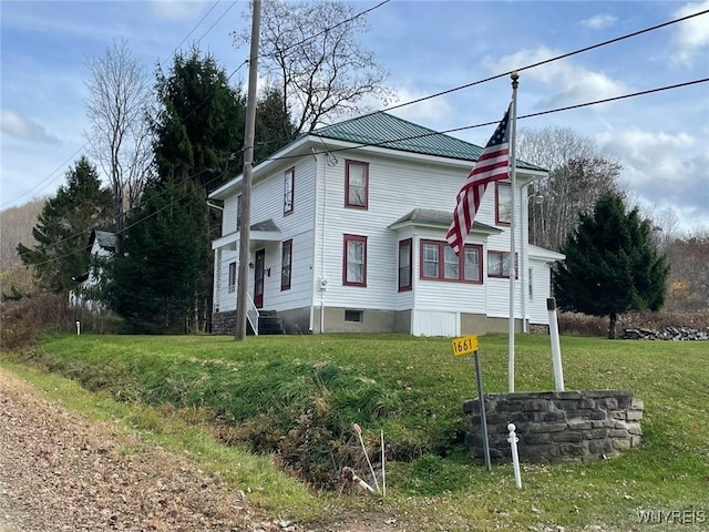 view of front of property featuring metal roof and a front lawn