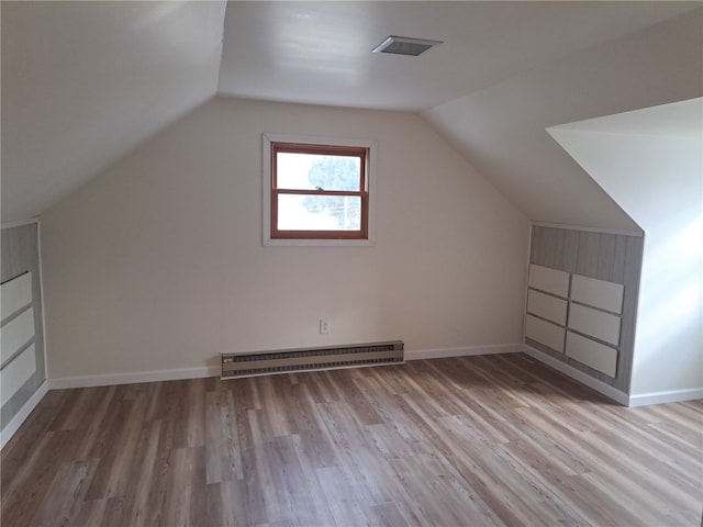 additional living space with lofted ceiling, wood finished floors, baseboards, and baseboard heating