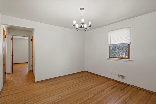 empty room with visible vents, an inviting chandelier, and light wood-style floors