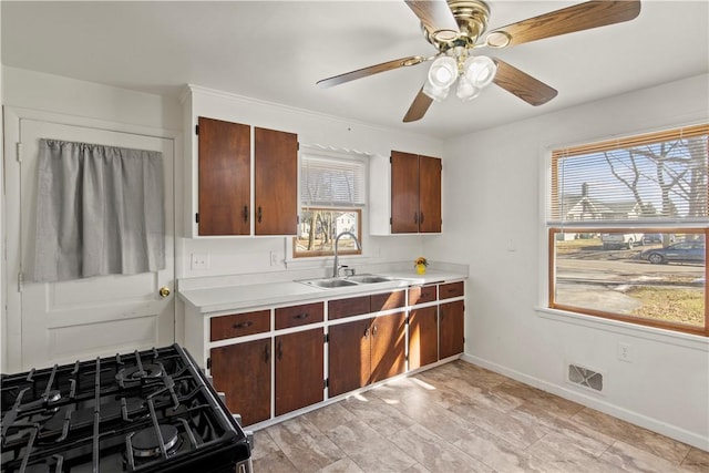 kitchen with black gas stove, light countertops, visible vents, and a sink