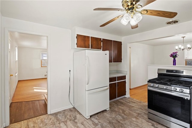 kitchen featuring visible vents, freestanding refrigerator, light wood finished floors, gas range, and dark brown cabinets