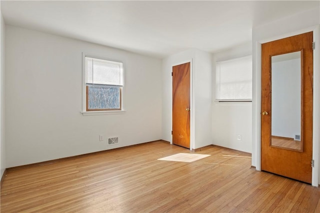 unfurnished bedroom featuring light wood-style floors, visible vents, and a closet