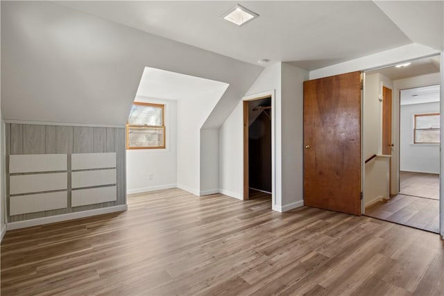 additional living space featuring baseboards, lofted ceiling, and wood finished floors