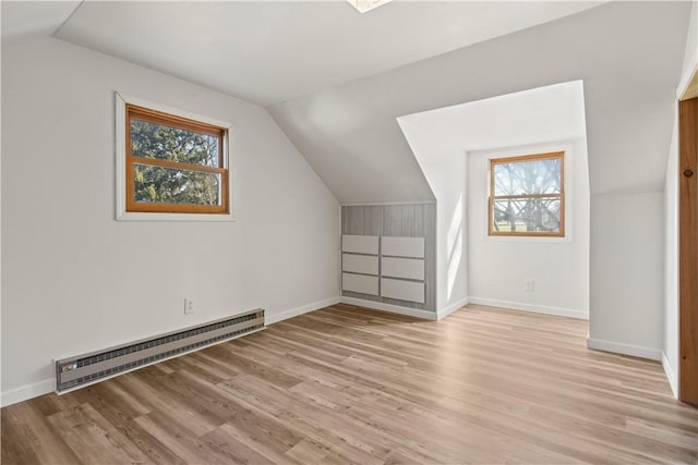 bonus room featuring a wealth of natural light, light wood-type flooring, baseboard heating, and vaulted ceiling