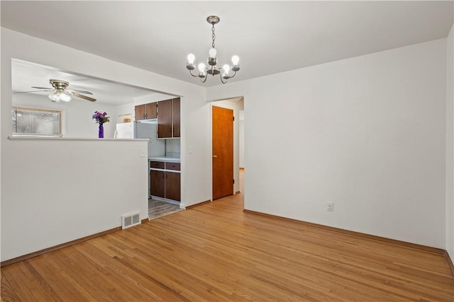 unfurnished room featuring ceiling fan with notable chandelier, visible vents, and light wood-type flooring