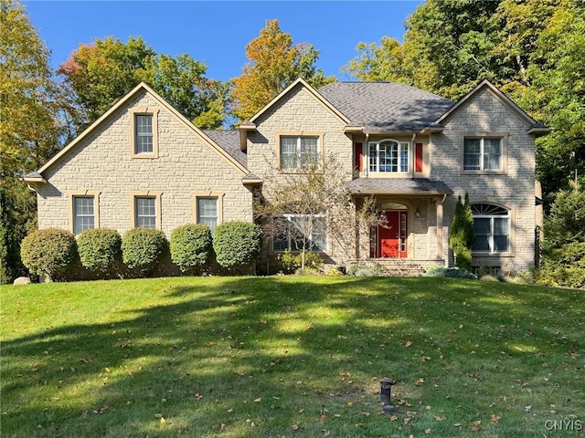 view of front facade with a front yard and a shingled roof