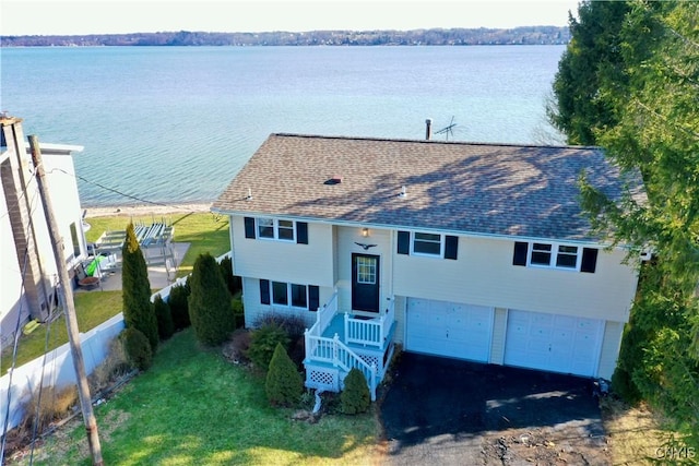 view of front of property with a water view, an attached garage, driveway, and a shingled roof