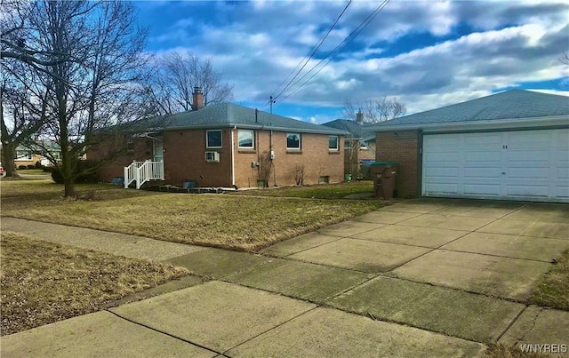 view of side of property featuring brick siding, a lawn, a chimney, a garage, and driveway