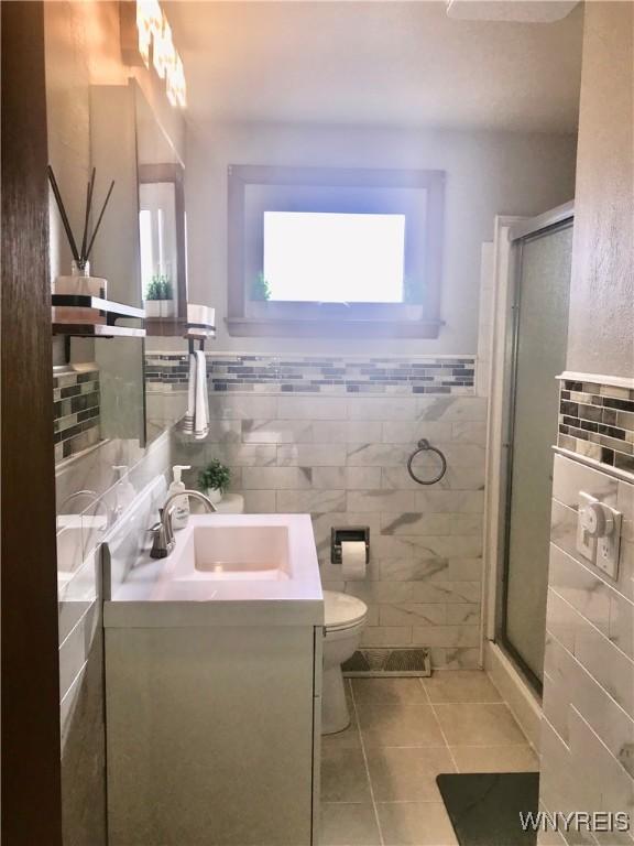 full bath with vanity, toilet, a stall shower, and tile patterned flooring