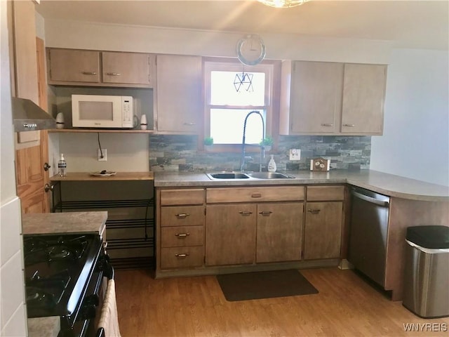 kitchen with stainless steel dishwasher, white microwave, light wood finished floors, and a sink