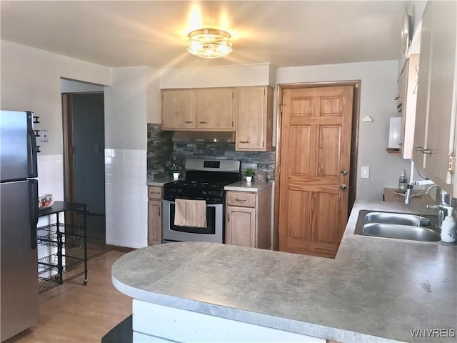 kitchen featuring a peninsula, light brown cabinetry, a sink, light countertops, and appliances with stainless steel finishes