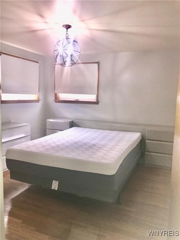 bedroom featuring an inviting chandelier and wood finished floors