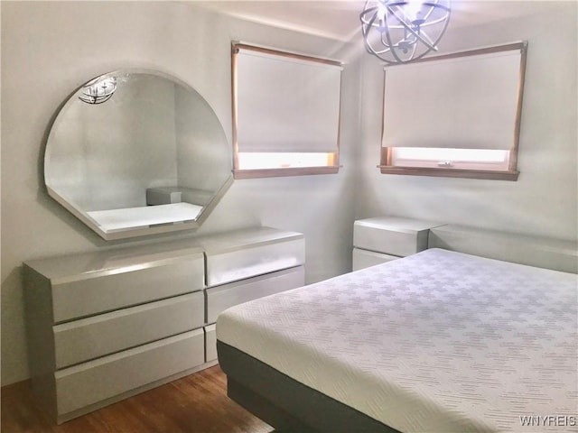 bedroom featuring an inviting chandelier and wood finished floors