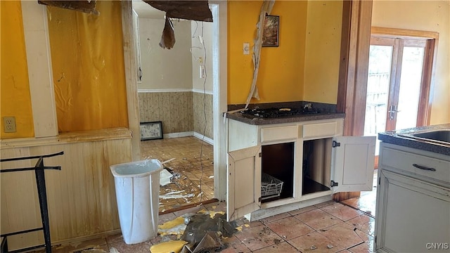 kitchen with light tile patterned floors, wainscoting, and gas cooktop