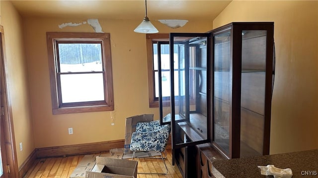 living area with light wood-style flooring, plenty of natural light, and baseboards