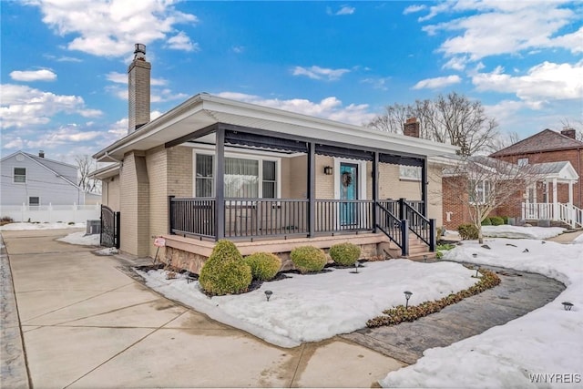 bungalow with brick siding, a porch, and a chimney