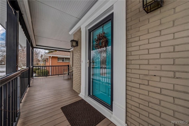 doorway to property featuring brick siding and covered porch