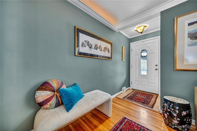 foyer entrance featuring wood finished floors, baseboards, and ornamental molding