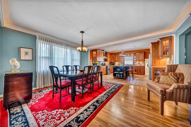 dining space with plenty of natural light, an inviting chandelier, light wood-style flooring, and ornamental molding