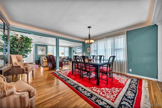 dining area featuring plenty of natural light, wood finished floors, baseboards, and a chandelier