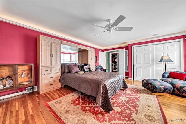 bedroom featuring ornamental molding, a baseboard heating unit, ceiling fan, and wood finished floors