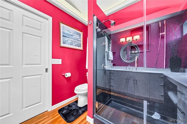 bathroom featuring vanity, wood finished floors, baseboards, a stall shower, and toilet