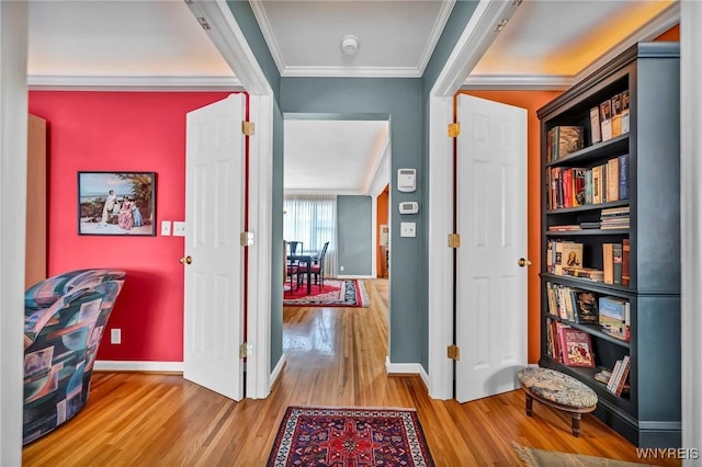 hallway featuring crown molding, wood finished floors, and baseboards