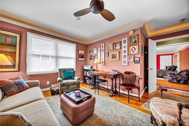 living room with ceiling fan, wood finished floors, baseboards, and ornamental molding