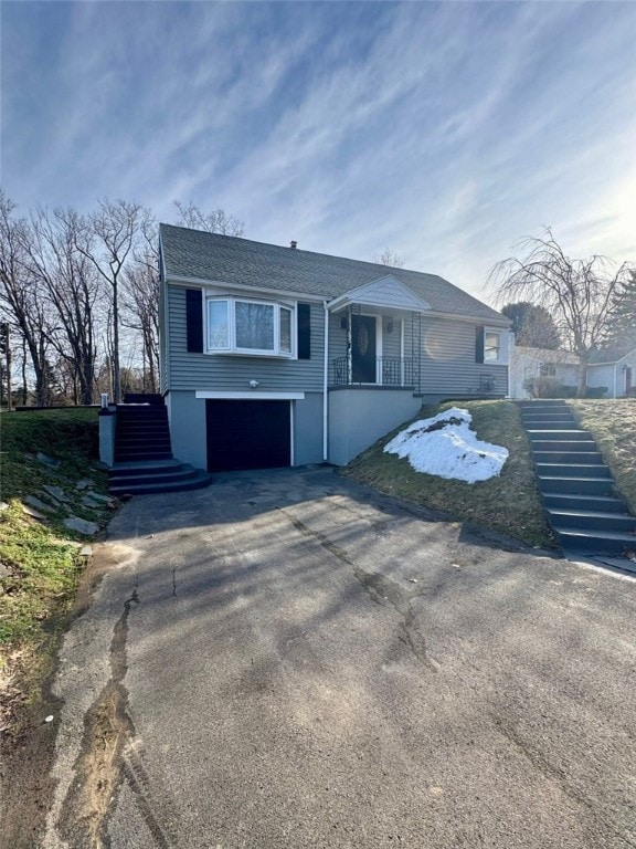 view of front of home featuring aphalt driveway, stairway, an attached garage, and a porch