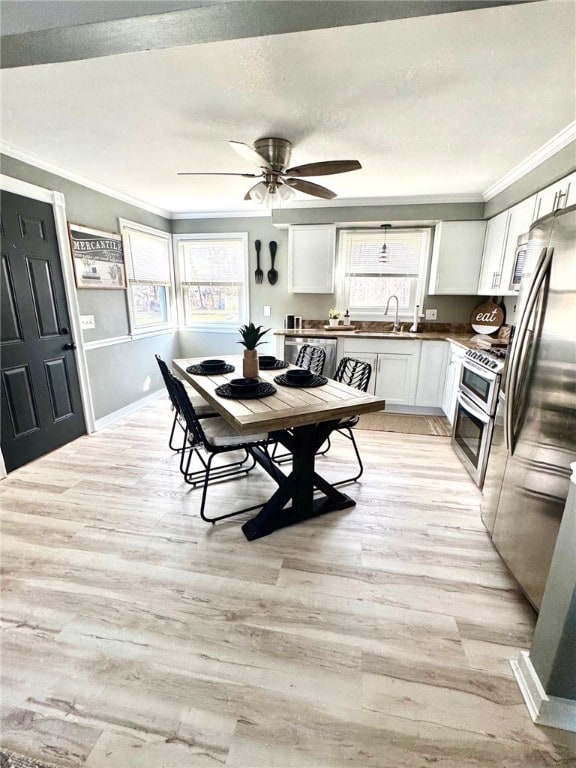 dining room with crown molding, light wood-style floors, a wealth of natural light, and a textured ceiling