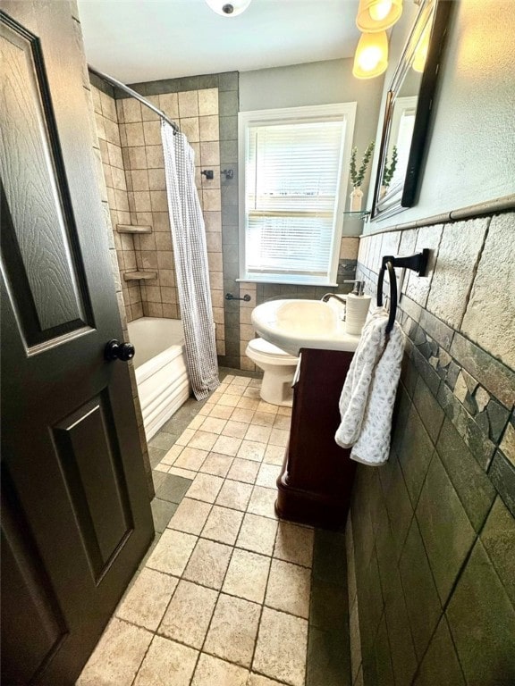 bathroom with a wainscoted wall, toilet, vanity, shower / bath combination with curtain, and tile walls