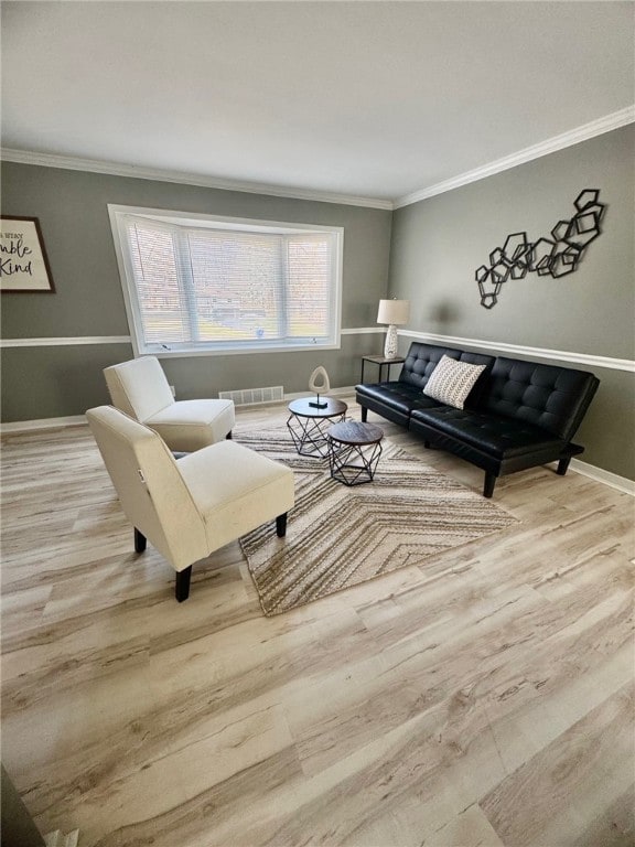 living area featuring visible vents, baseboards, wood finished floors, and crown molding